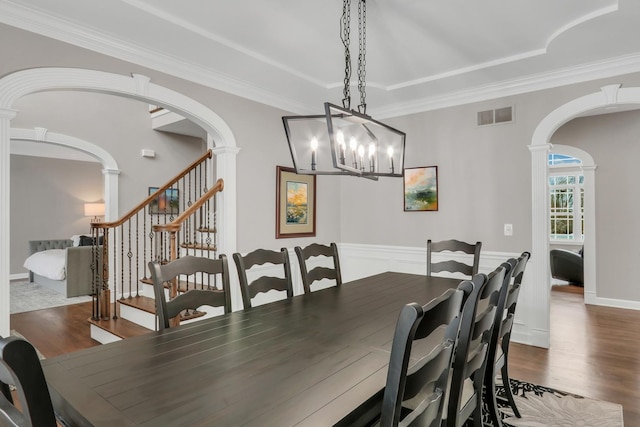 dining area with ornate columns, dark hardwood / wood-style flooring, ornamental molding, and a notable chandelier