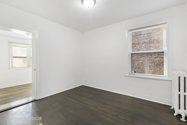 unfurnished room with dark hardwood / wood-style floors and radiator heating unit