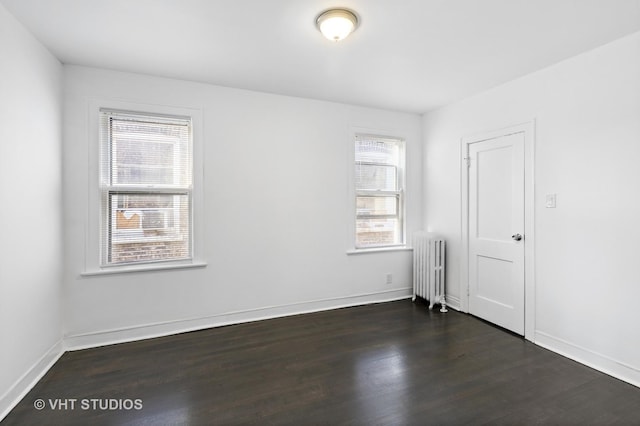 spare room featuring radiator and dark hardwood / wood-style floors