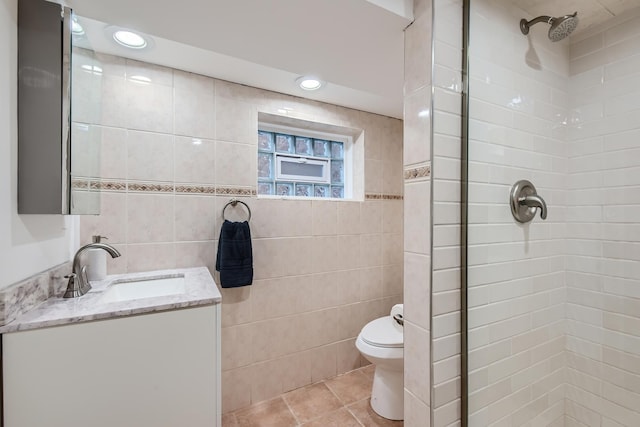 bathroom with a tile shower, vanity, tile walls, tile patterned flooring, and toilet