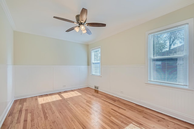 empty room with ceiling fan, crown molding, and light wood-type flooring