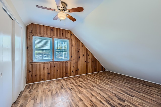 bonus room featuring hardwood / wood-style flooring, vaulted ceiling, ceiling fan, and wooden walls