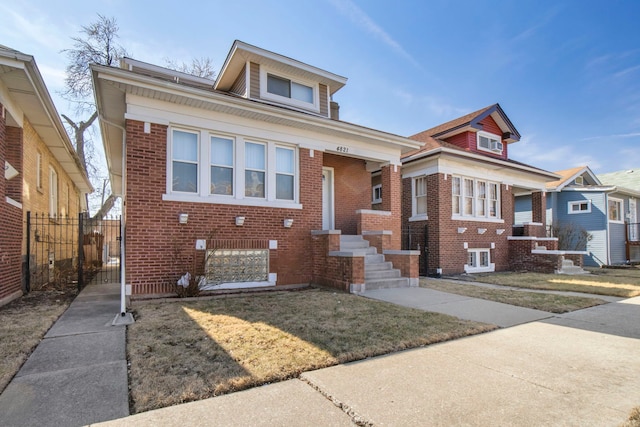 view of front facade with brick siding, a front lawn, and fence