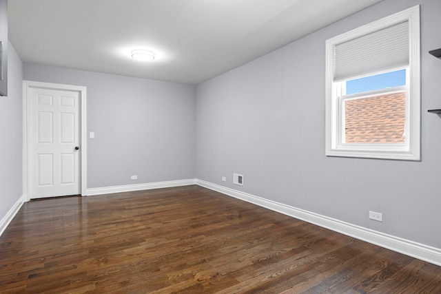 spare room featuring visible vents, dark wood-type flooring, and baseboards