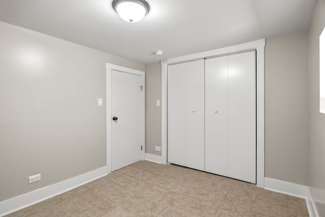 unfurnished bedroom with light tile patterned floors, a closet, and baseboards