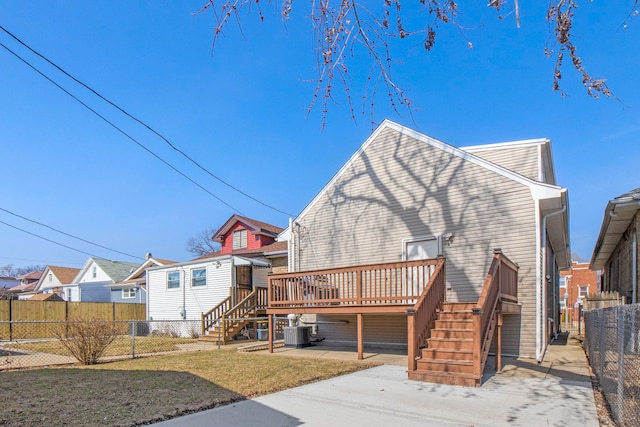 rear view of property with fence, a wooden deck, central AC, a patio area, and a lawn