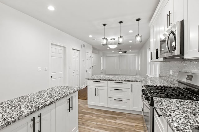 kitchen with white cabinetry, a peninsula, tasteful backsplash, and appliances with stainless steel finishes