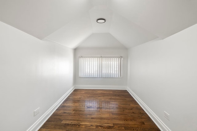 unfurnished room featuring dark wood-style floors, lofted ceiling, and baseboards