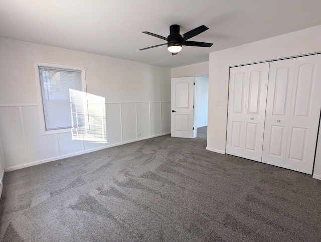 unfurnished bedroom featuring ceiling fan, dark carpet, and a closet