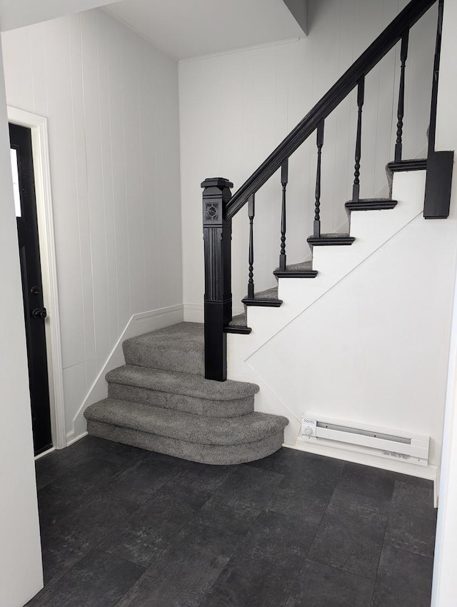 stairway featuring a baseboard radiator and wooden walls