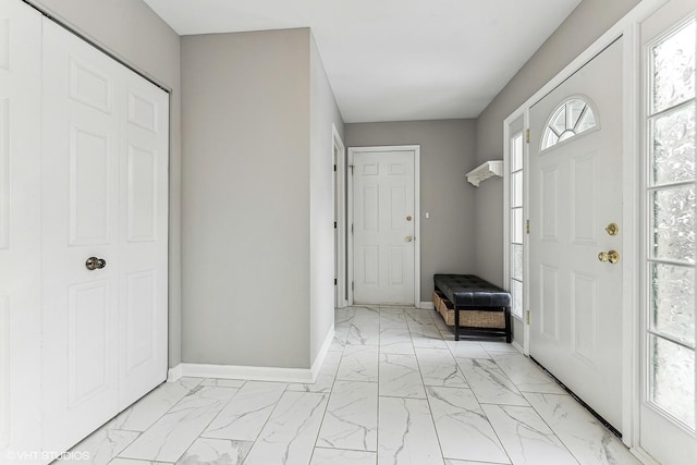 foyer entrance with marble finish floor and baseboards