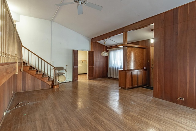 unfurnished living room featuring hardwood / wood-style flooring, ceiling fan, wood walls, and lofted ceiling