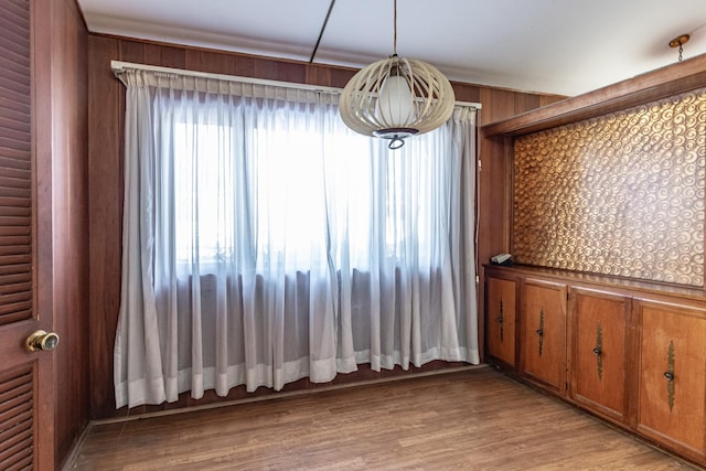 unfurnished dining area with wooden walls and light hardwood / wood-style flooring