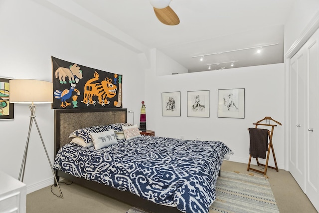 bedroom with carpet flooring, rail lighting, ceiling fan, and a closet