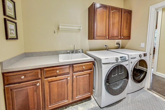 clothes washing area with sink, cabinets, and washer and clothes dryer