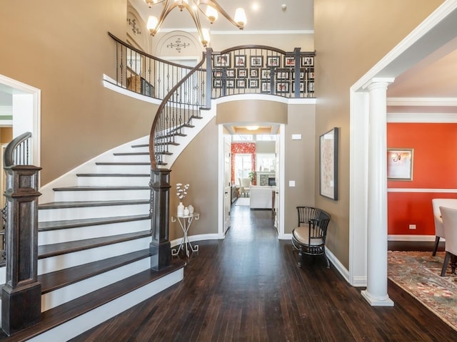 entryway featuring a chandelier, ornate columns, ornamental molding, dark hardwood / wood-style flooring, and a high ceiling