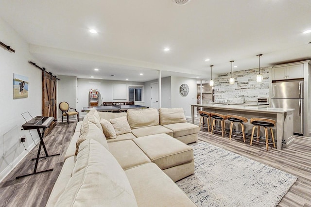 living room featuring pool table, wet bar, light hardwood / wood-style floors, and a barn door