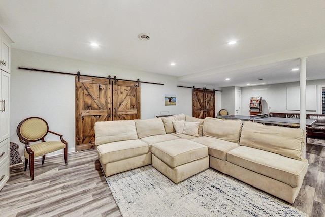 living room featuring a barn door and light hardwood / wood-style flooring