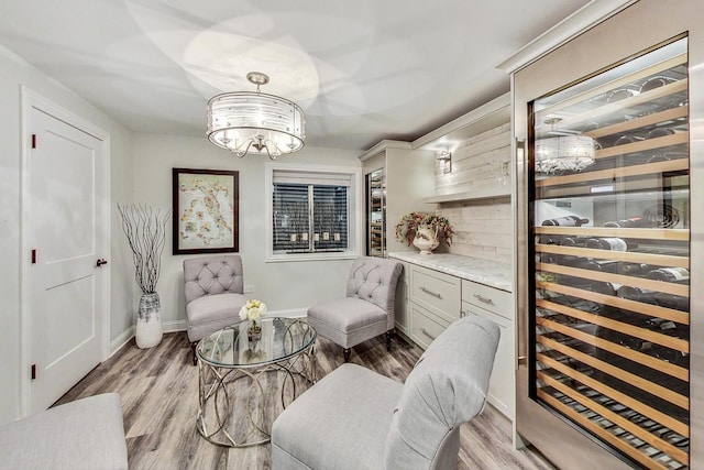 living area with a notable chandelier, light wood-type flooring, and wine cooler