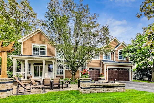 view of front of property featuring a front yard, a garage, and a patio