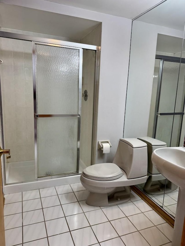 bathroom featuring tile patterned floors, a shower with door, and toilet