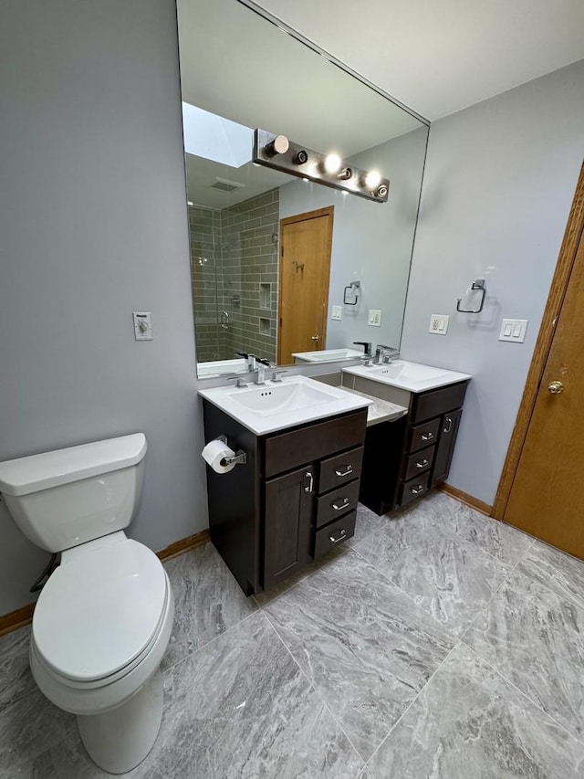 bathroom with vanity, toilet, and a tile shower