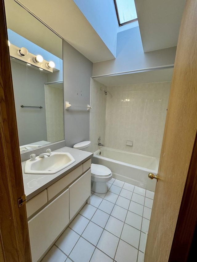 full bathroom featuring a skylight, vanity, tile patterned flooring, toilet, and tiled shower / bath