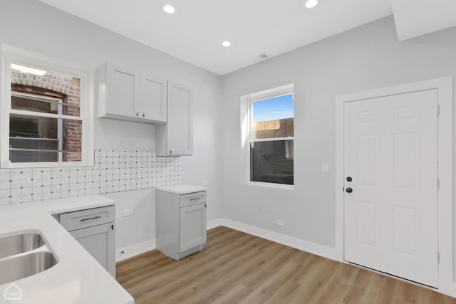 kitchen featuring backsplash, light hardwood / wood-style floors, and sink