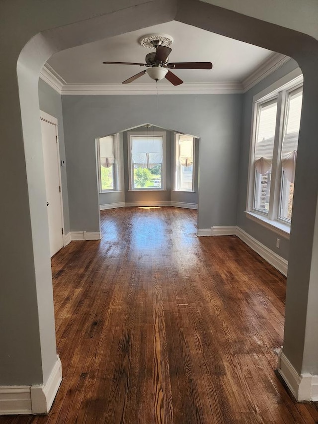 spare room with crown molding, ceiling fan, a healthy amount of sunlight, and dark hardwood / wood-style floors