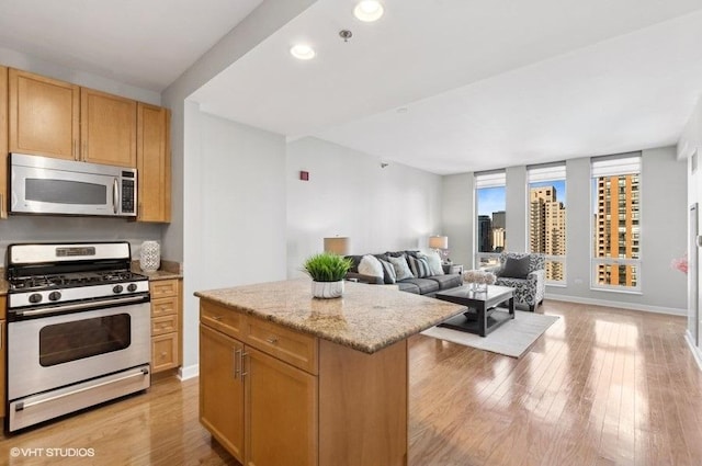 kitchen featuring light hardwood / wood-style floors, a kitchen island, light stone countertops, and gas range oven