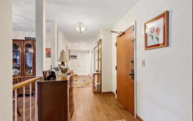 hallway with a textured ceiling and light wood-type flooring