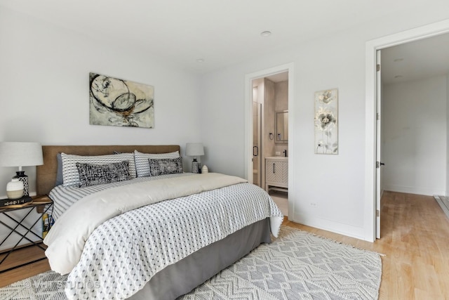 bedroom featuring ensuite bathroom and light wood-type flooring