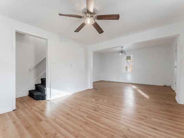 spare room featuring ceiling fan with notable chandelier and light hardwood / wood-style floors