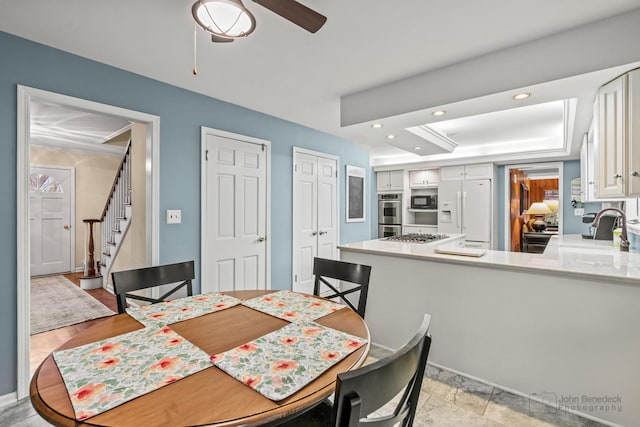 dining area featuring a tray ceiling, ceiling fan, and sink