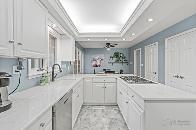 kitchen with kitchen peninsula, appliances with stainless steel finishes, white cabinetry, and ceiling fan