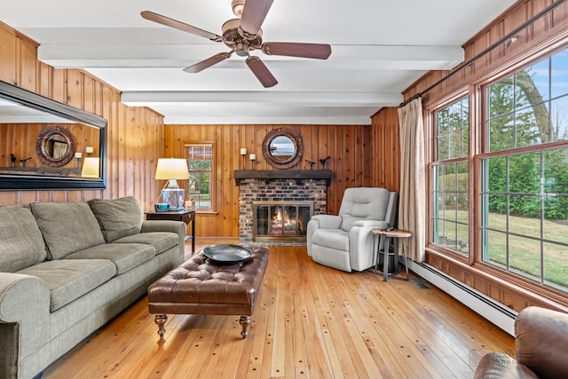 living room featuring ceiling fan, a baseboard radiator, beamed ceiling, light hardwood / wood-style floors, and a fireplace