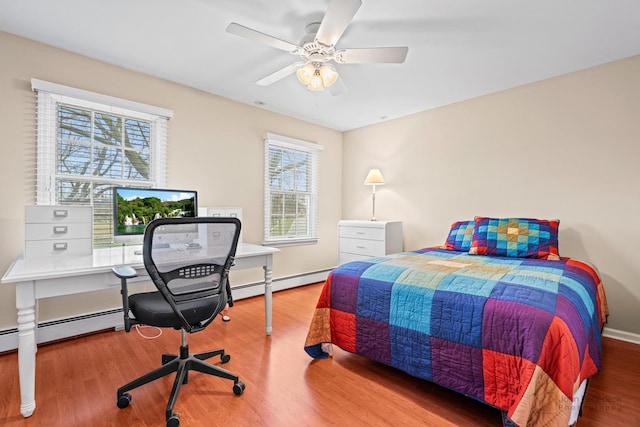 bedroom with hardwood / wood-style floors, ceiling fan, multiple windows, and a baseboard radiator