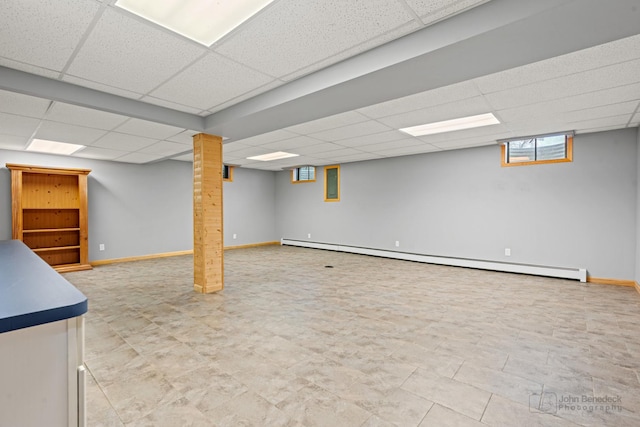 basement featuring baseboard heating and a drop ceiling