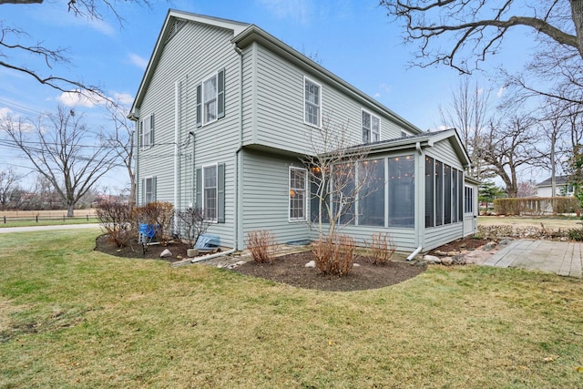 rear view of property with a lawn and a sunroom