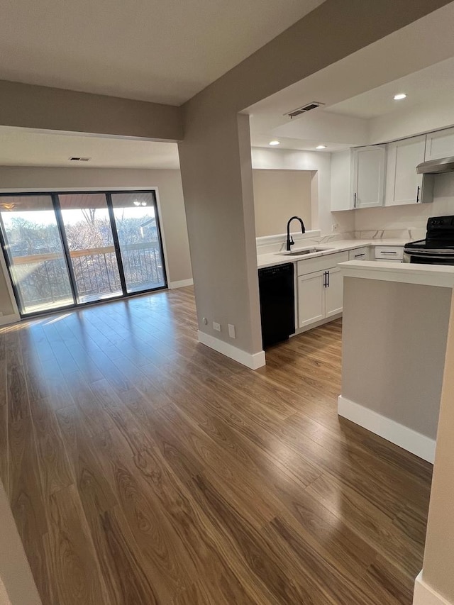 kitchen with extractor fan, sink, black appliances, hardwood / wood-style floors, and white cabinetry