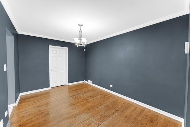 unfurnished room featuring wood-type flooring, crown molding, and a notable chandelier