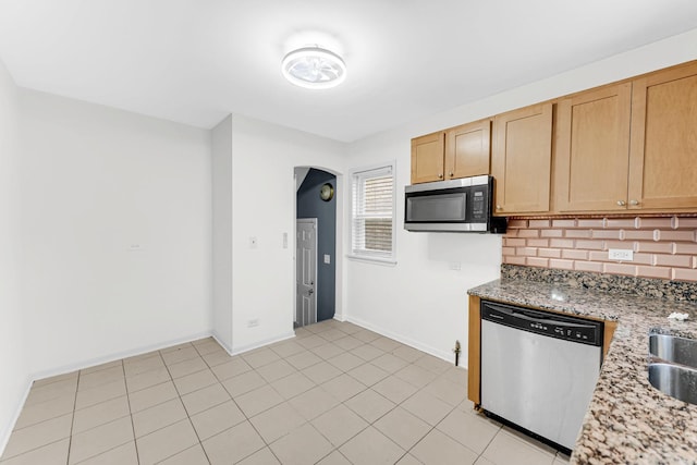 kitchen featuring light stone countertops, stainless steel appliances, decorative backsplash, light brown cabinetry, and light tile patterned floors