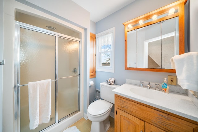 bathroom featuring a shower with door, vanity, and toilet