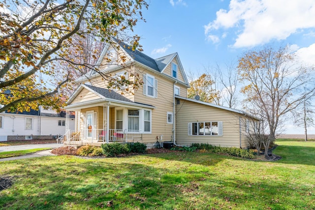 view of front facade featuring central AC, covered porch, and a front yard