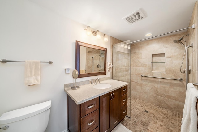 bathroom with tiled shower, vanity, and toilet