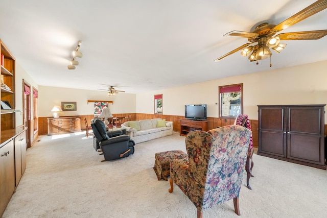 carpeted living room with ceiling fan and wood walls