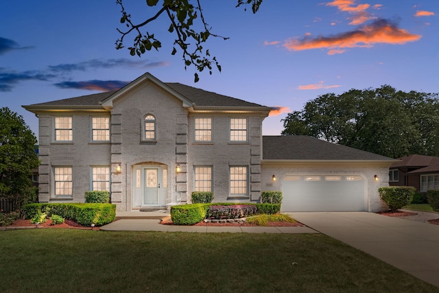 colonial house featuring a lawn and a garage