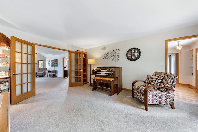 sitting room with light carpet, lofted ceiling, and french doors