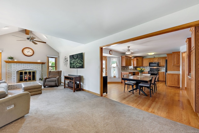 carpeted living room featuring a brick fireplace, vaulted ceiling with beams, and ceiling fan