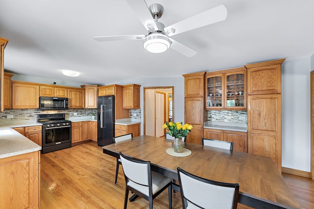 kitchen with ceiling fan, backsplash, black appliances, and light hardwood / wood-style flooring